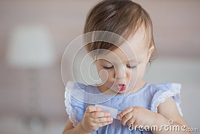 Portrait of a cute little baby girl in a blue dress plays with a plastic thing Stock Photo
