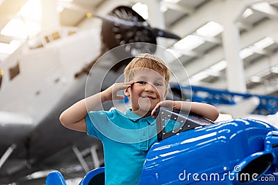 Portrait of cute little blond happy kid boy enjoy have fun play riding pedat toz plane model against vintage airplane Stock Photo