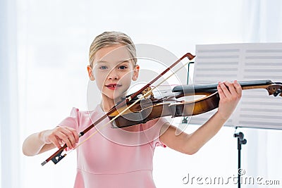 portrait of cute little child in pink dress playing violin Stock Photo