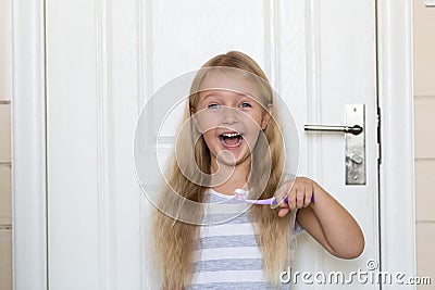 Portrait of cute little girl with blonde hair which cleaning tooth with brush and toothpaste in bathroom Stock Photo