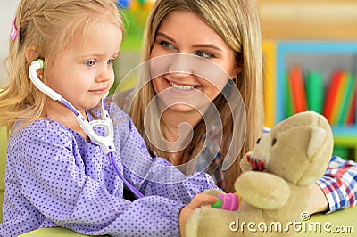 Portrait of cute little girl playing nurse, inspecting teddy bear with stethoscope Stock Photo