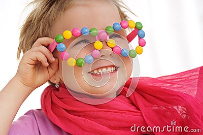 Portrait of cute little girl wearing funny glasses, decorated with colorful smarties, candies Stock Photo