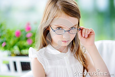 Portrait of cute little girl wearing glasses at home. Vision, health, ophthalmology concept. Stock Photo