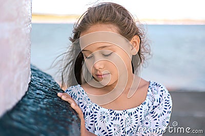 Portrait of cute lonely sad little girl, standing thoughtfully at the seaside. Stock Photo