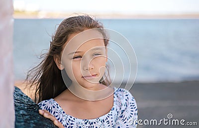 Portrait of cute lonely sad little girl, standing thoughtfully at the seaside. Stock Photo