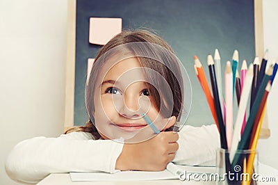 Portrait of cute lovely girl drawing in copybook on blackboard b Stock Photo