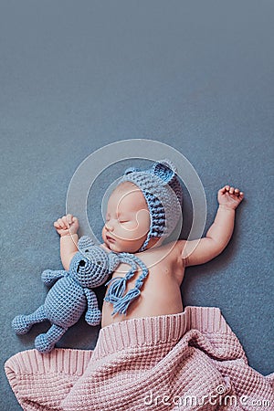 Cute newborn baby girl sleeping with teddy bear on gray blanket. Stock Photo