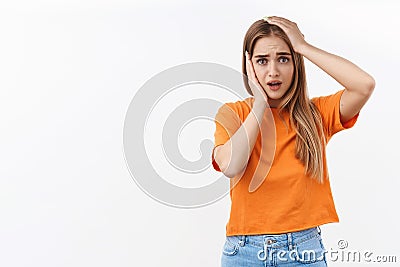 Portrait of cute silly, insecure blond girl in panic, hold hands on head troubled, dont know what do, alarmed staring Stock Photo