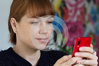 Portrait of the cute smiling middle aged woman looking at mobile phone Stock Photo
