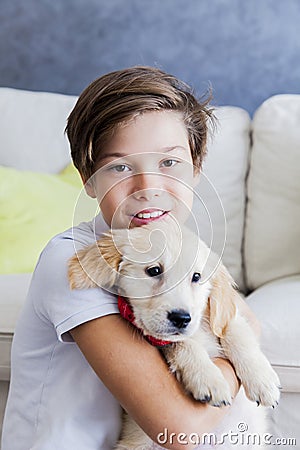 Cute teen boy with baby retriever dog in room Stock Photo