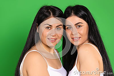 Portrait of cute twins brunettes on a green background. Posing and smiling looking at the camera. Stock Photo