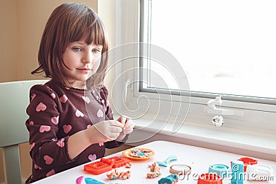 White Caucasian preschooler girl playing plasticine playdough indoors at home Stock Photo
