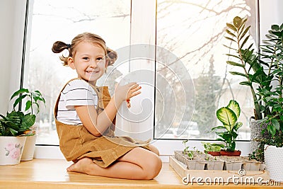 Portrait of a cutie little girl sitting on a sill with water spray in hands Stock Photo