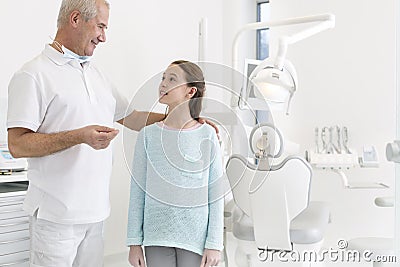 Portrait of dentist talking to girl patient at dental clinic Stock Photo