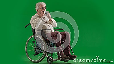 Portrait of disabled man isolated on chroma key green screen full shot. Senior bearded man sitting in wheelchair holding Stock Photo