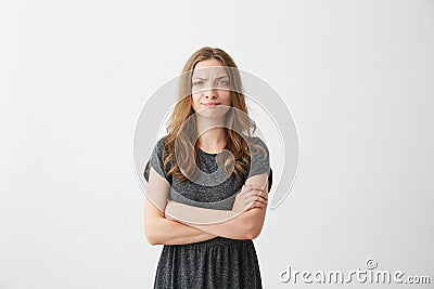 Portrait of displeased young pretty girl looking at camera with contempt over white background. Crossed arms. Stock Photo