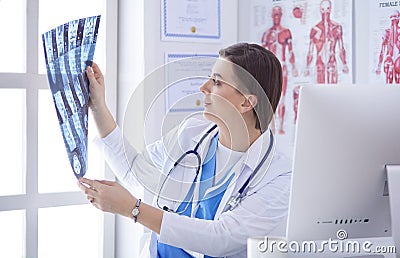 Portrait of doctor sitting in office holding xray image, working on computer Stock Photo