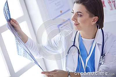 Portrait of doctor sitting in office holding xray image, working on computer Stock Photo