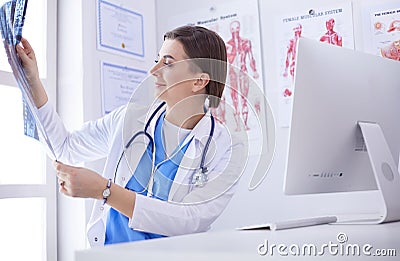 Portrait of doctor sitting in office holding xray image, working on computer Stock Photo