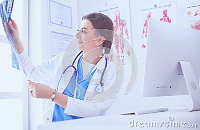 Portrait of doctor sitting in office holding xray image, working on computer Stock Photo