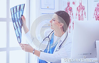 Portrait of doctor sitting in office holding xray image, working on computer Stock Photo