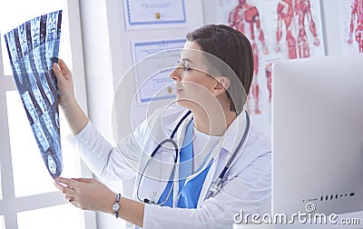 Portrait of doctor sitting in office holding xray image, working on computer Stock Photo