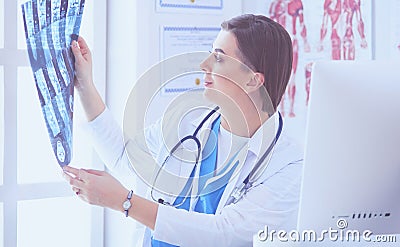 Portrait of doctor sitting in office holding xray image, working on computer Stock Photo