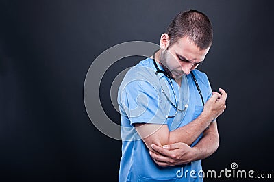 Portrait of doctor wearing scrubs having elbow pain Stock Photo