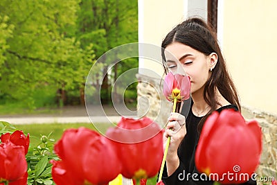 Portrait of dreaming pretty young teen girl behind red tulips Stock Photo