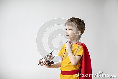 Portrait Dreamy boy in a red cape plays with a toy airplane Stock Photo