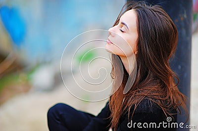 Portrait of a dreamy cute happy woman worker meditating outdoors with big eyes closed, sitting with the effect of blur closeup. De Stock Photo