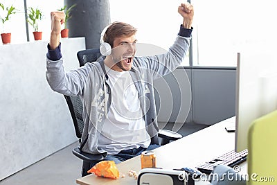 Portrait of ecstatic gamer guy in headphones screaming and rejoicing while playing video games on computer Stock Photo