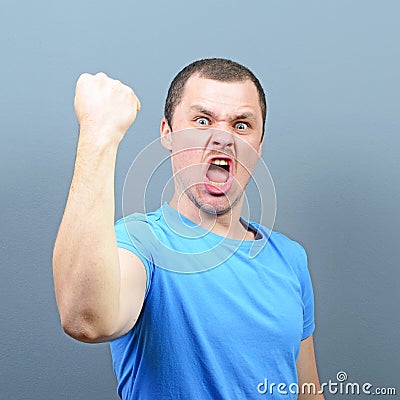 Portrait of ecstatic young man celebrating victory or win against gray background Stock Photo