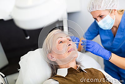 Elderly wman receiving procedure of face mesotherapy at cosmetology clinic Stock Photo