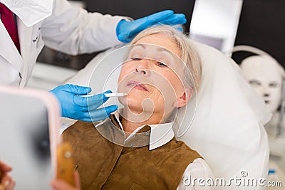 Elderly wman receiving procedure of face mesotherapy at cosmetology clinic Stock Photo