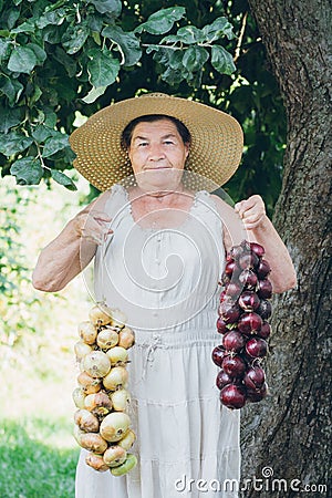 Portrait of an elderly woman in a hat holding a onions Stock Photo