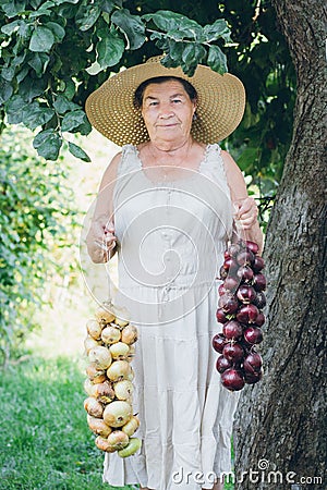 Portrait of an elderly woman in a hat holding a onions Stock Photo