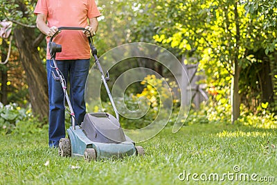 Portrait of eldery senior man working in the summer garden walking on a grass field Stock Photo