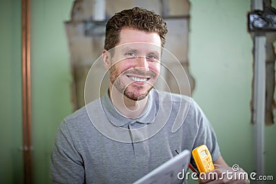Portrait Of Electrician Inside House Being Renovated Studying Plans Stock Photo