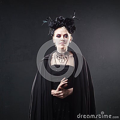 Portrait of an elegant Gothic blonde woman. Girl in wreath of black flowers and black cloak Stock Photo