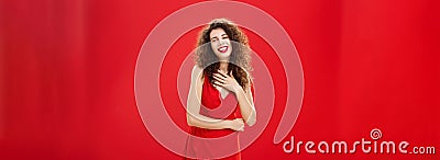 Portrait of elegant pleased and grateful charming caucasian woman with curly hairstyle holding palm on chest smiling and Stock Photo