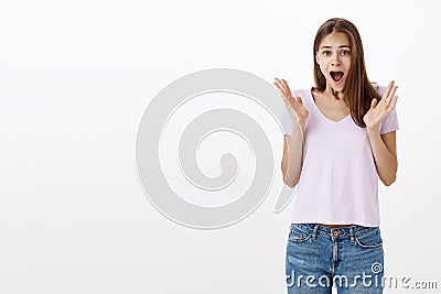 Portrait of emotive pretty young european female student in casual t-shirt yelling from amazement and joy raising and Stock Photo