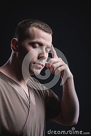 Portrait of an enlightened Caucasian male physiotherapist Closing your eyes. The telepath holds his fingers to the Stock Photo