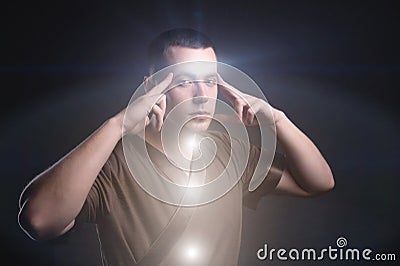 Portrait of an enlightened Caucasian male physiotherapist with glowing chakras. The telepath holds his fingers to the Stock Photo