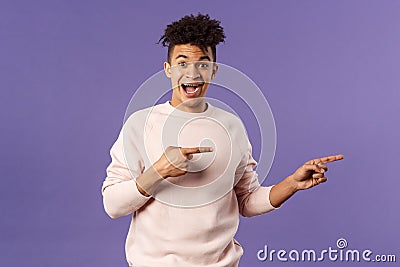 Portrait of enthusiastic lively hipster male 25s, pointing fingers right inviting join courses, sign up for awesome deal Stock Photo