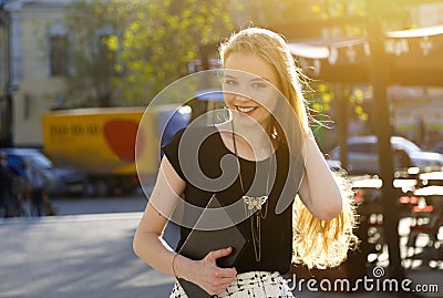 Portrait of european smiling woman with laptop walking on city street Stock Photo