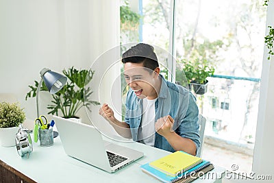 Portrait of excited asian young man working on laptop computer a Stock Photo