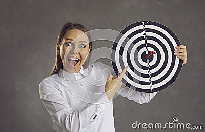 Portrait of excited businesswoman pointing finger at target with dart right in bullseye Stock Photo