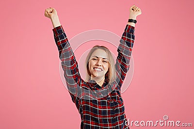 Portrait of excited joyful glad female raises hands, celebrates great success, expresses her happiness, feels to be winner, reciev Stock Photo