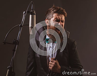 Portrait of excited man in a recording studio. Expressive bearded man in suit with microphone. Karaoke signer, musical Stock Photo